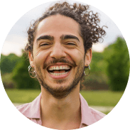 Joyful young man with curly hair laughing in park